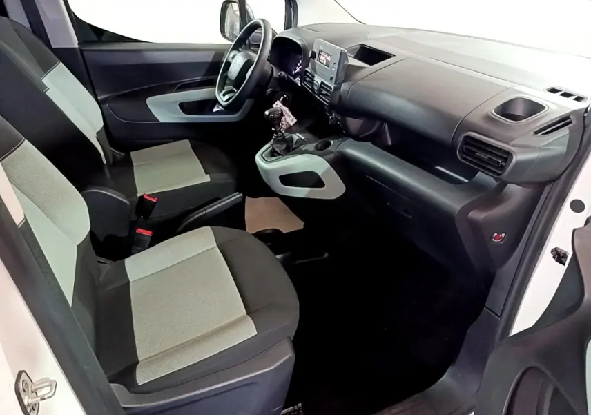 Vue intérieure côté conducteur du Citroën Berlingo XL blanc, montrant les sièges bicolores et le tableau de bord avec écran central.