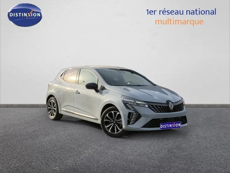 Renault Clio 1.6 E-Tech gris Rafale en 3/4 avant droit, avec calandre distinctive et jantes noires bicolores.