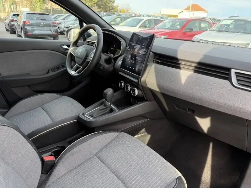 Vue intérieure côté conducteur de la Renault Clio 1.6 E-Tech 145ch hybride 2025 avec sellerie grise et écran tactile vertical.