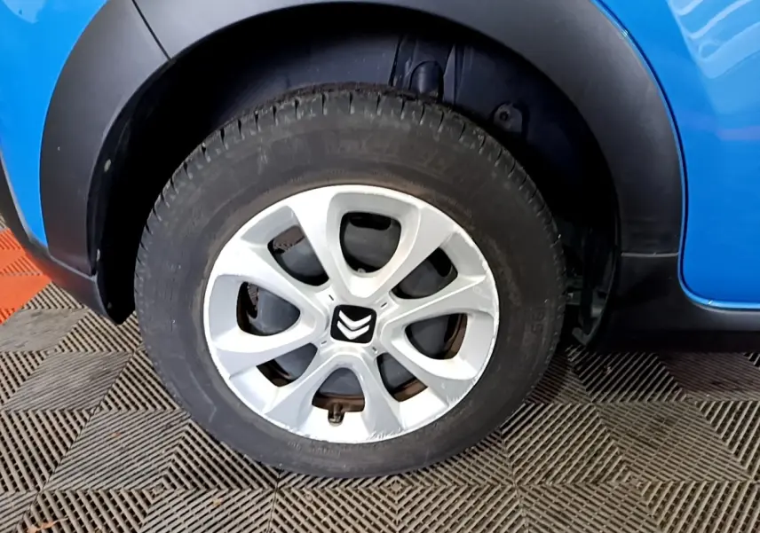 Gros plan sur la roue avant droite d'une Citroën C3 bleu avec jante argentée et logo Citroën central.