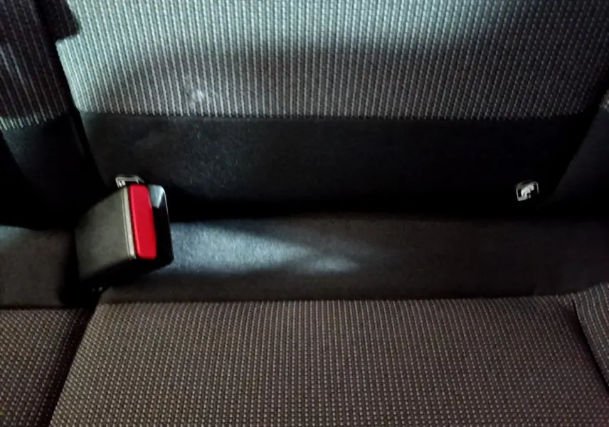 Gros plan sur la banquette arrière grise de la Citroën C3 avec boucle de ceinture de sécurité rouge visible.