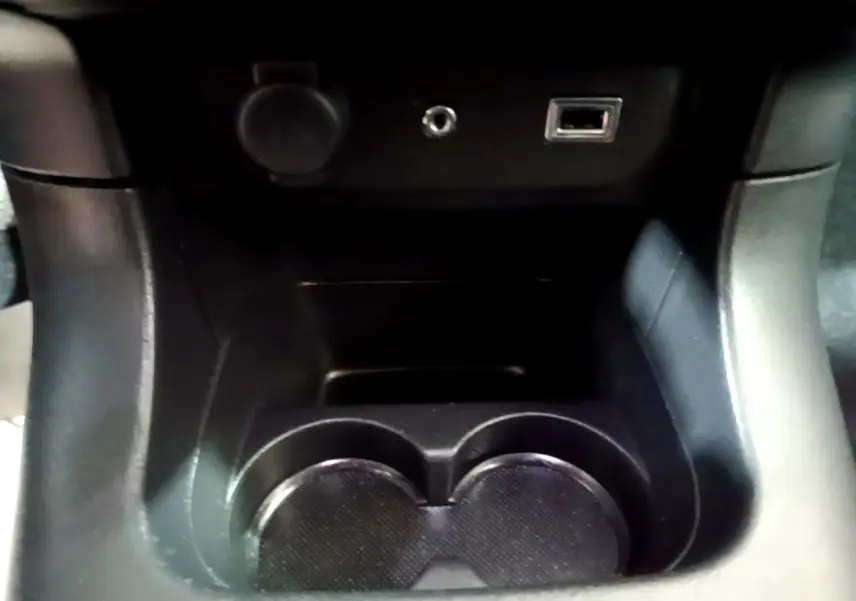 Gros plan sur la console centrale noire de la Citroën C3 2017, montrant porte-gobelets et prises USB et auxiliaire.