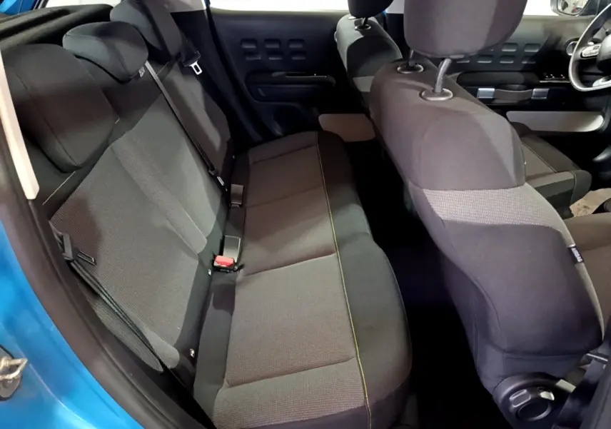 Vue intérieure arrière côté gauche de la Citroën C3 bleu, montrant la banquette arrière et les sièges avant en tissu noir.
