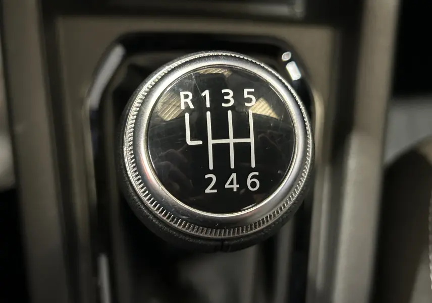 Gros plan sur le levier de vitesse manuel noir de la Renault Clio V Bluetci 100 Evolution, avec marquages blancs.