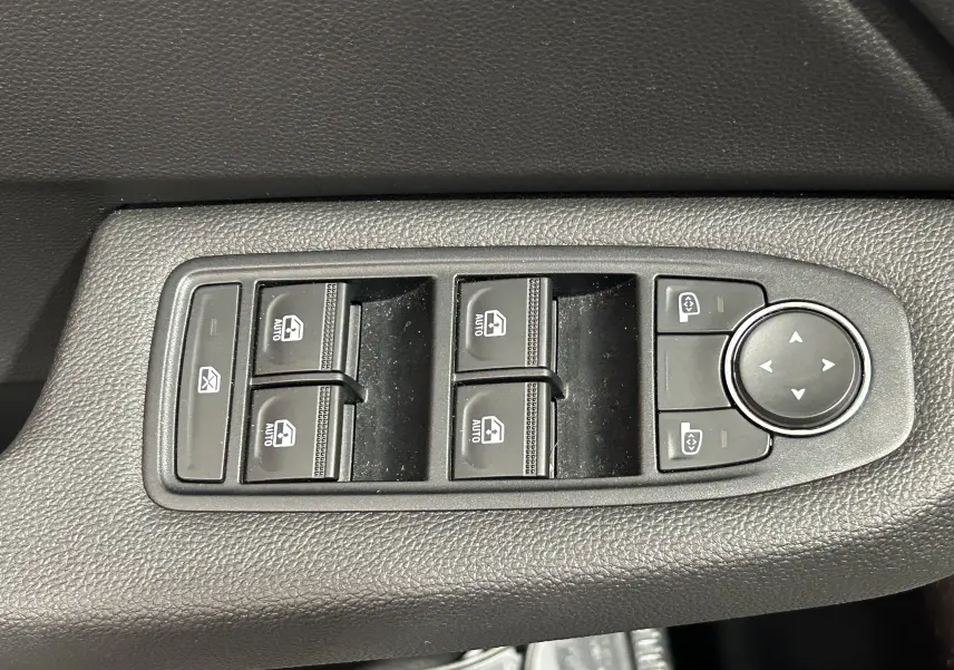 Panneau de commandes des vitres électriques et réglages des rétroviseurs sur la portière intérieure d'une Renault Clio V noire.