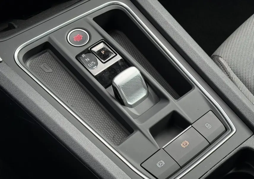 Gros plan sur la console centrale grise avec levier de vitesses automatique et bouton start/stop dans une SEAT Leon blanche.