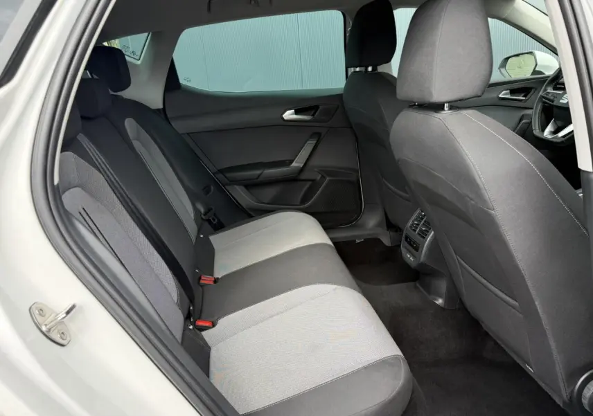 Vue intérieure côté gauche montrant la banquette arrière grise et noire du SEAT LEON blanc 2025.