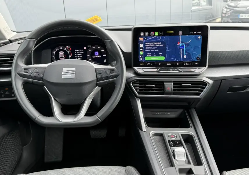 Vue intérieure frontale du tableau de bord et volant cuir noir de la SEAT LEON 1.5 TSI 2025 avec écran tactile et affichage numérique.