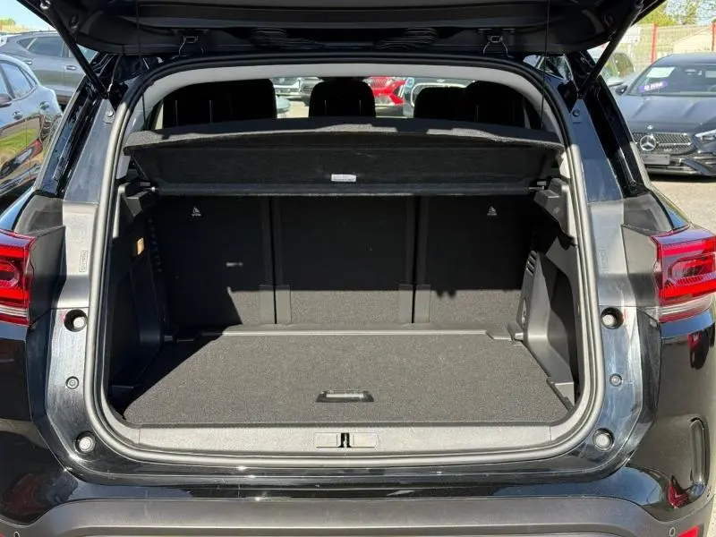 Coffre ouvert vu de l'arrière d'un Citroën C5 Aircross noir Perla Nera avec cache-bagages déployé.