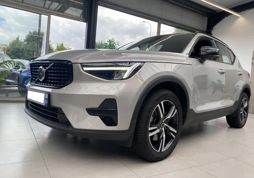 Volvo XC40 B3 163ch Plus DCT 7 argent aurore métallisé vu en 3/4 avant droit, avec calandre noire et jantes alliage bicolores.