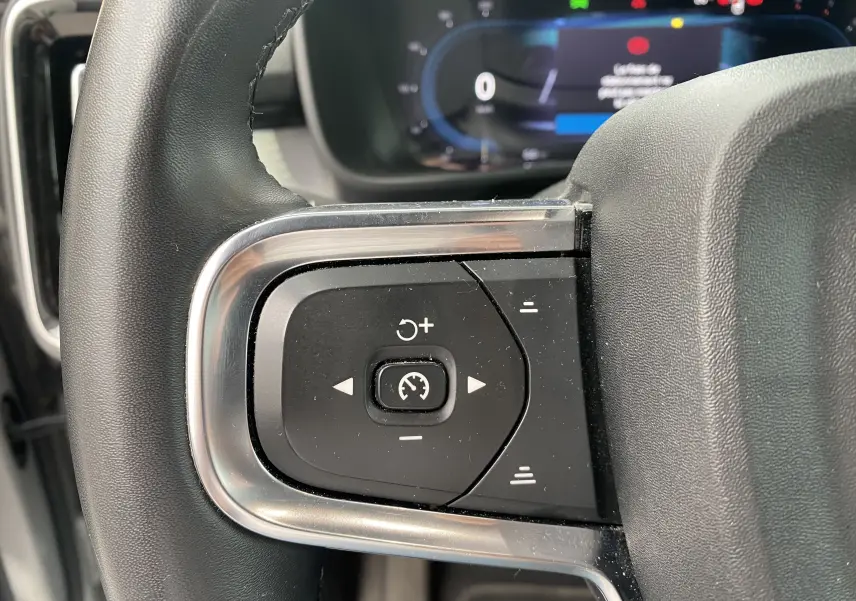 Gros plan sur les commandes de régulateur de vitesse au volant d'un Volvo XC40 2023, finition argent métallisé.