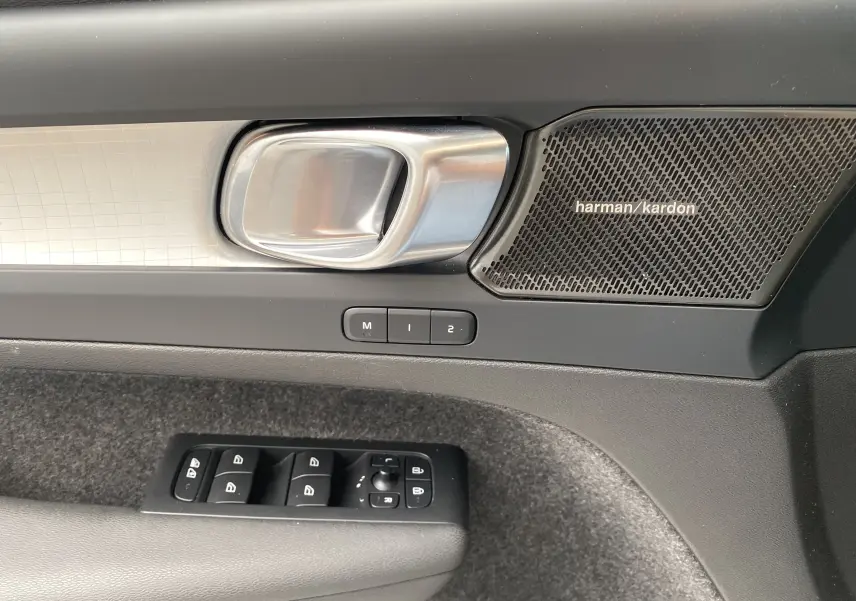 Poignée de porte intérieure côté gauche du Volvo XC40 2023 avec haut-parleur Harman Kardon et commandes des vitres.