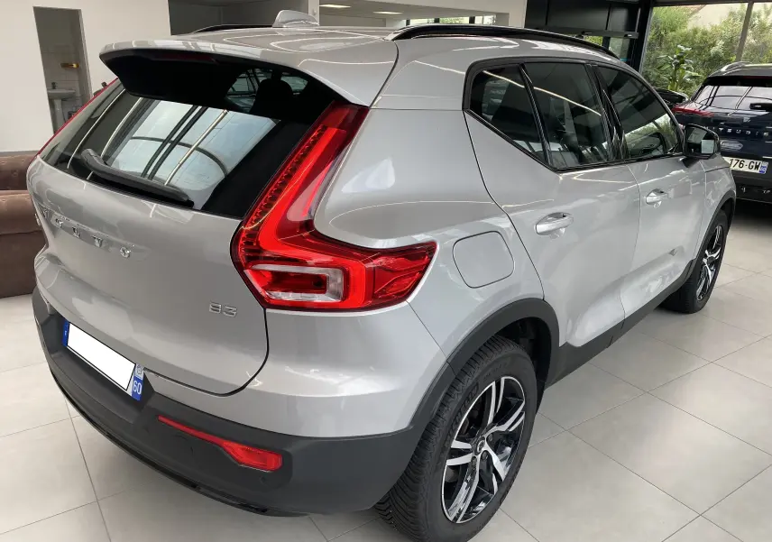 Vue 3/4 arrière droite d'un Volvo XC40 B3 argent aurore métallisé avec feux LED et jantes alliage en showroom.