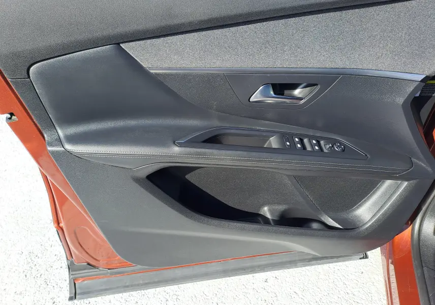 Gros plan sur la porte avant gauche métallique copper du Peugeot 3008 2019 avec commandes de vitres et poignée intégrée.
