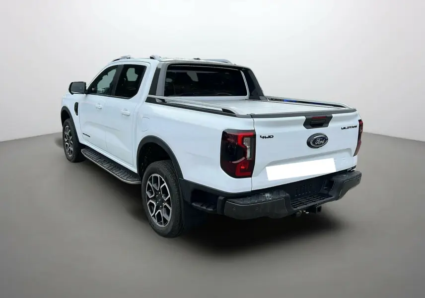 Ford Ranger 2025 blanc glacier en 3/4 arrière droit, version Wildtrak Plus avec benne couverte et jantes alliage.