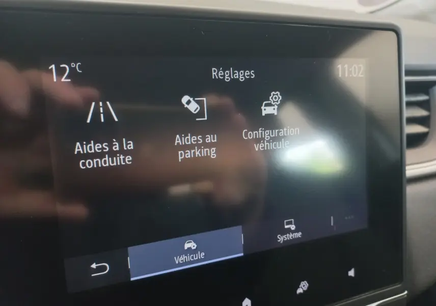 Écran tactile central du tableau de bord du Renault Captur Business TCe 100 affichant les réglages d'aides à la conduite et au parking.