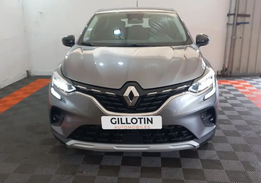 Vue frontale d'un Renault Captur Business TCe 100 gris clair avec feux LED allumés et calandre noire brillante.