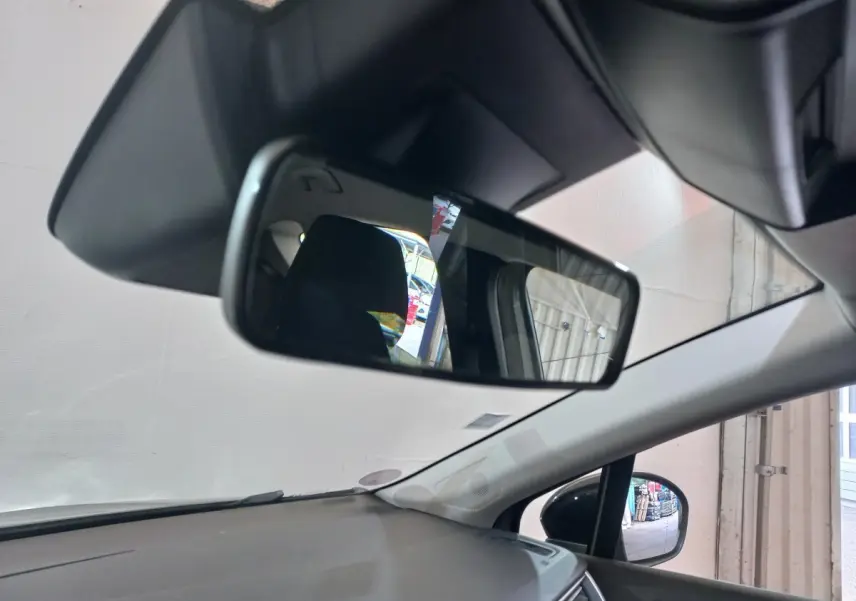 Vue intérieure du rétroviseur central et du tableau de bord gris clair du Renault Captur Business TCe 100, angle avant droit.