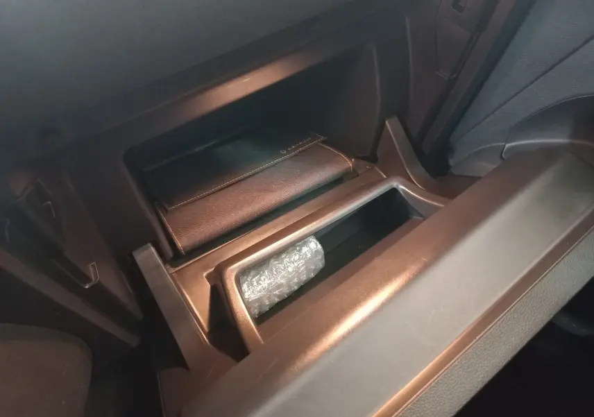 Gros plan sur la boîte à gants ouverte du Renault Captur Business gris clair, avec un étui en cuir marqué Renault.