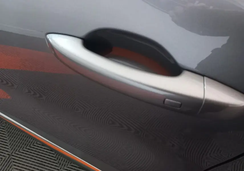 Poignée de porte côté gauche gris clair du Renault Captur Business TCe 100 2020 avec bouton de déverrouillage intégré.