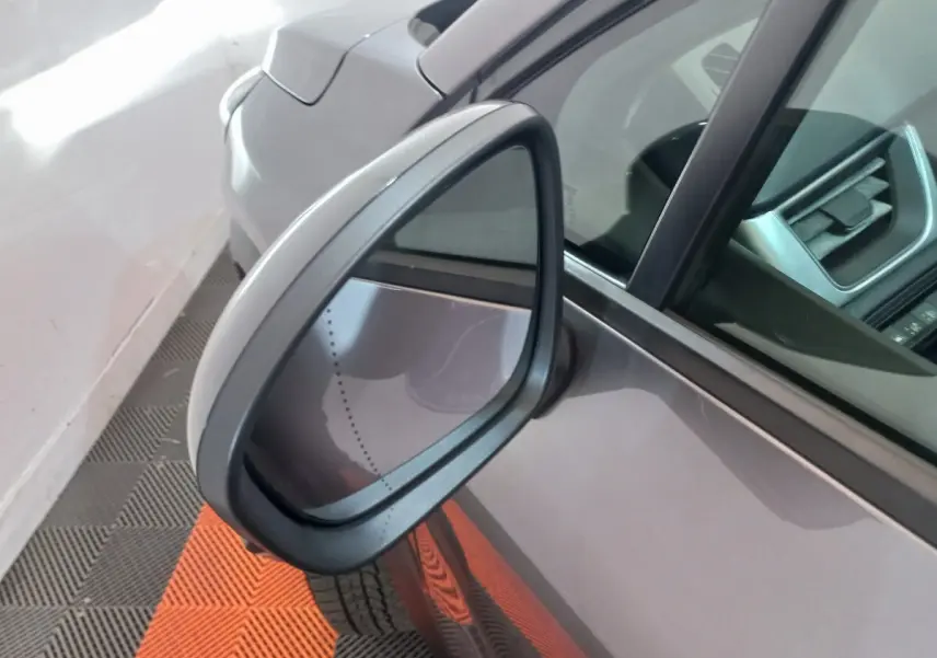 Rétroviseur côté gauche d'un Renault Captur Business gris clair, avec partie de la portière et intérieur visible.