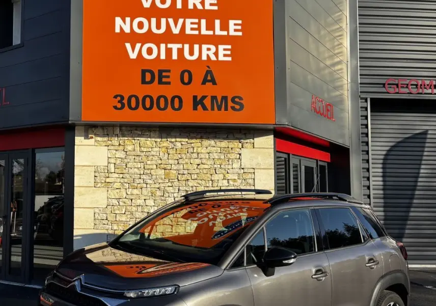 Citroën C3 Aircross gris foncé vue 3/4 avant droit, avec barres de toit noires et jantes alliage distinctives.