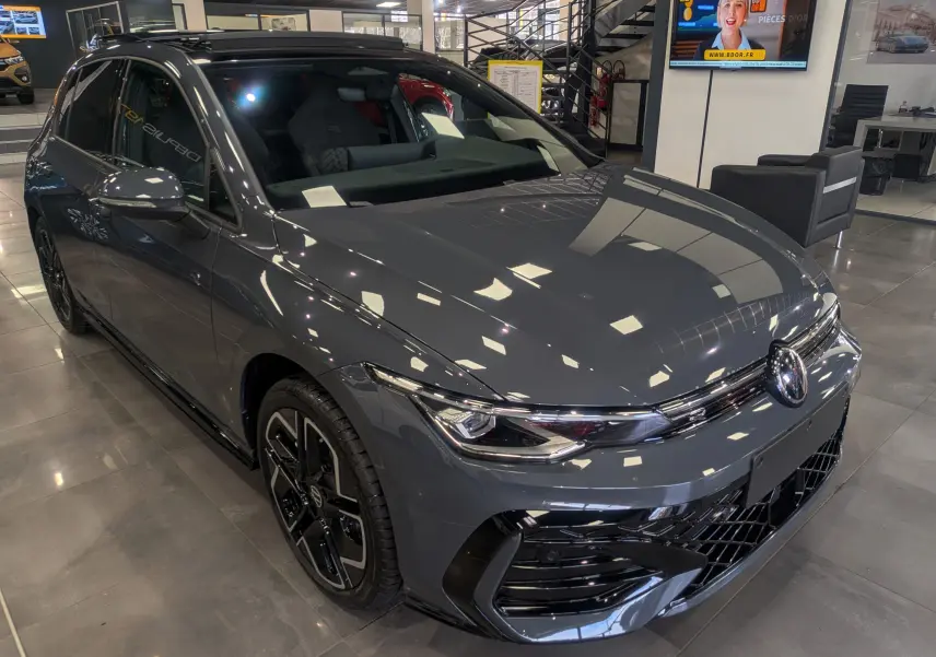 Vue 3/4 avant d'une Volkswagen Golf 1.5 eTSI R-Line gris dauphin avec jantes noires en concession.