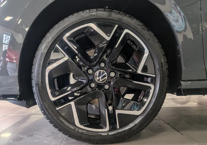 Gros plan sur la jante noire et argentée d’une Volkswagen Golf gris dauphin, côté droit du véhicule.