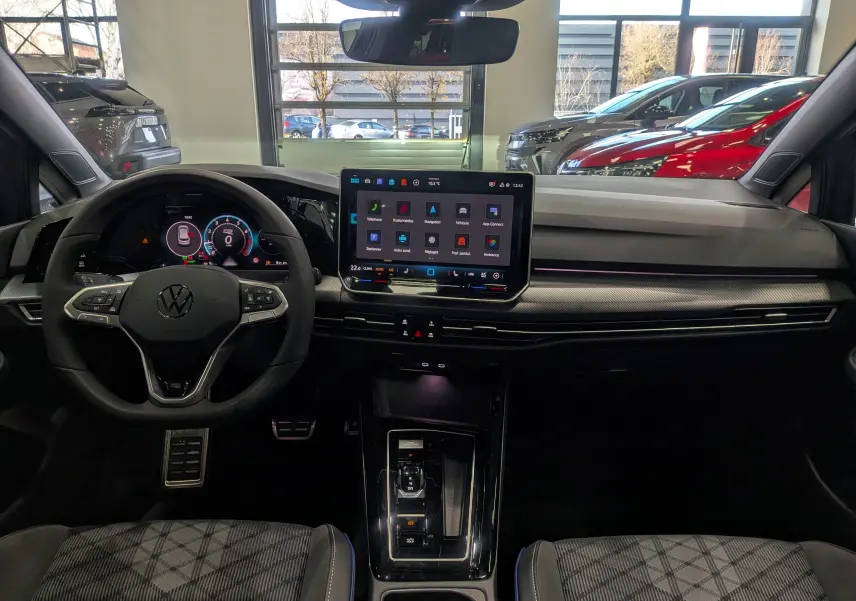 Vue intérieure frontale du tableau de bord de la Volkswagen Golf 1.5 eTSI gris dauphin avec écran tactile central et volant multifonction.