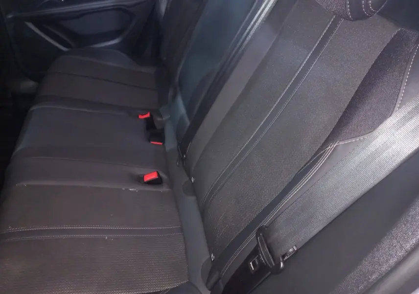 Vue rapprochée de la banquette arrière noire du Peugeot 3008, montrant les ceintures et les boucles rouges.