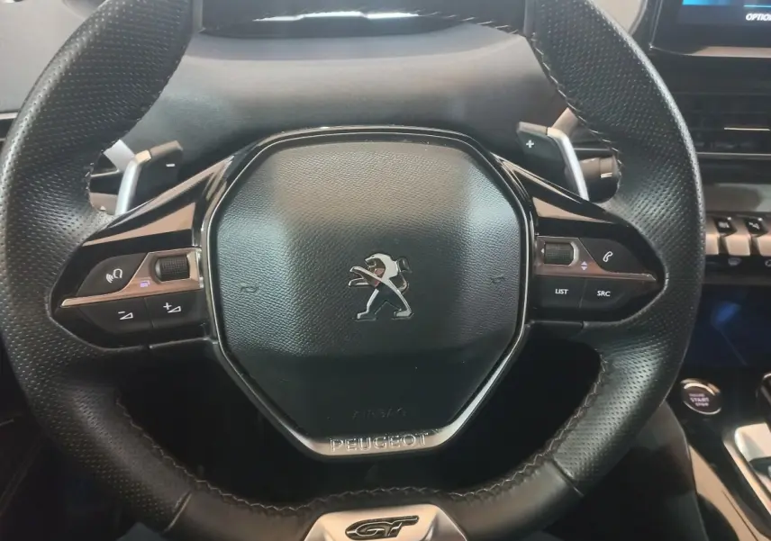 Vue rapprochée du volant cuir noir avec logo Peugeot et badge GT du SUV 3008 gris clair 2022.