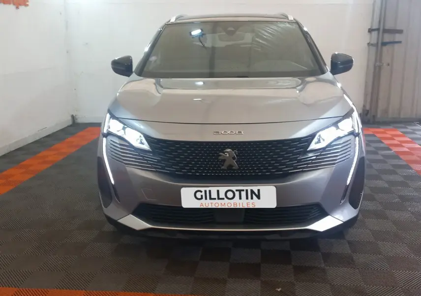 Vue frontale d'un Peugeot 3008 gris clair 2022 avec calandre noire et feux LED allumés en intérieur.