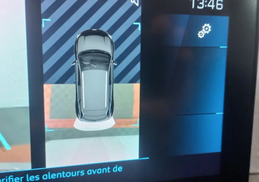 Affichage écran tactile montrant vue aérienne du Peugeot 3008 gris clair en aide au stationnement arrière.
