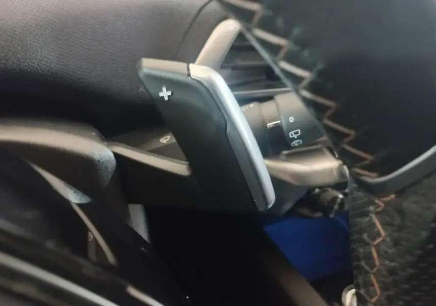 Gros plan sur la palette de changement de vitesse "+" côté droit du volant cuir du Peugeot 3008 gris clair 2022.