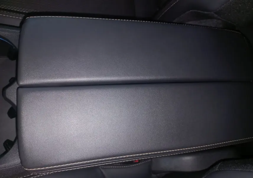 Gros plan sur l'accoudoir central en cuir noir avec surpiqûres contrastées dans l'habitacle du Peugeot 3008 gris clair.