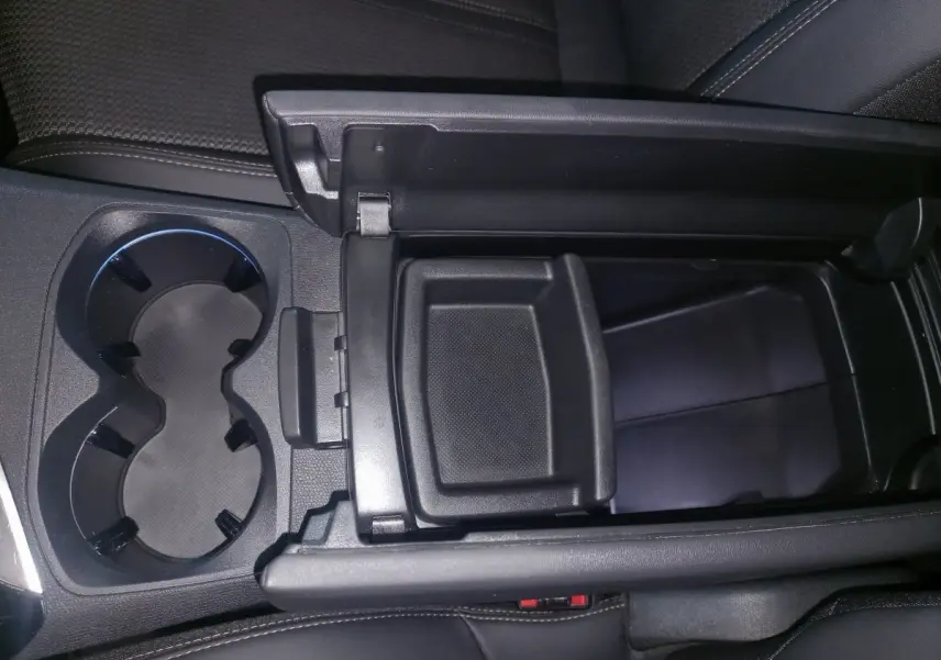 Vue rapprochée de la console centrale ouverte avec porte-gobelets et rangement noir dans un Peugeot 3008 gris clair 2022.