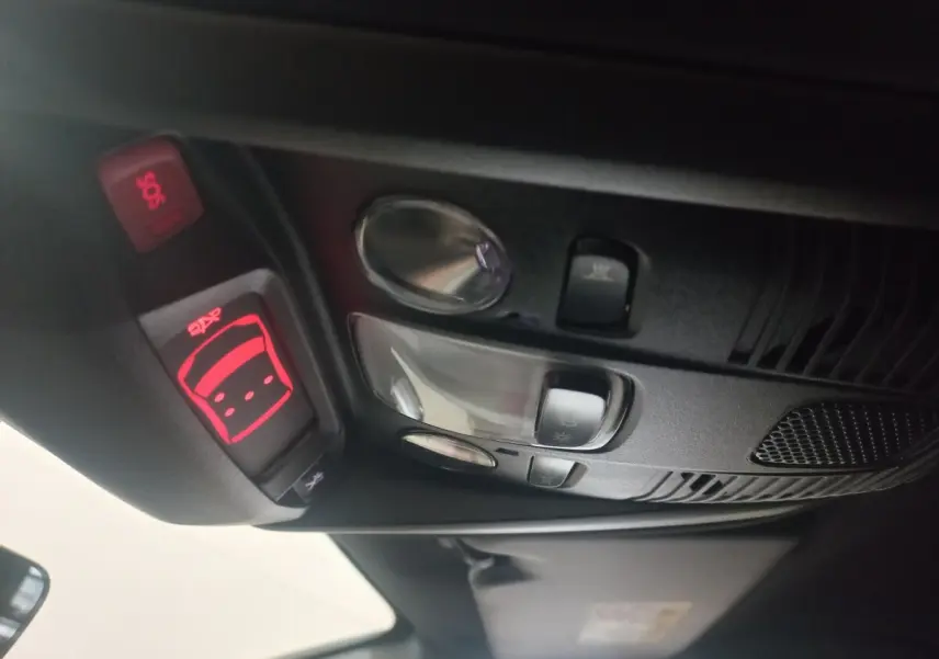 Vue intérieure en gros plan du plafonnier avec commandes d’éclairage et bouton SOS rouge du Peugeot 3008 gris clair 2022.