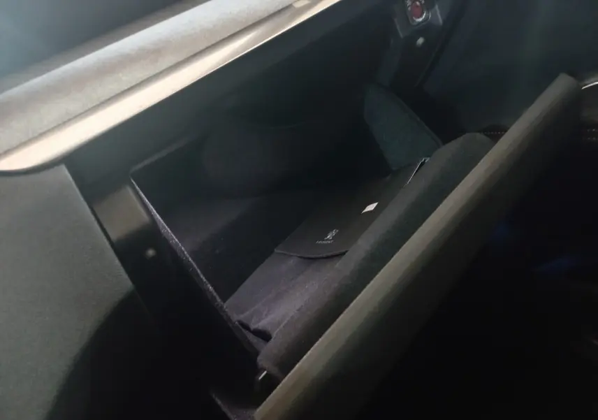Vue rapprochée de la boîte à gants ouverte du Peugeot 3008 gris clair, montrant un étui noir à l'intérieur.
