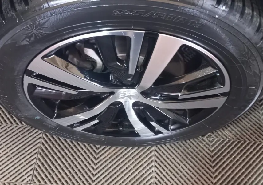 Gros plan sur la jante alliage bicolore noir et argentée du Peugeot 3008 gris clair, mettant en valeur le logo central.