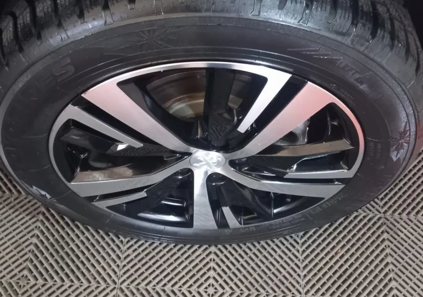 Gros plan sur la jante alliage bicolore noire et argentée du Peugeot 3008 gris clair, vue de dessus.