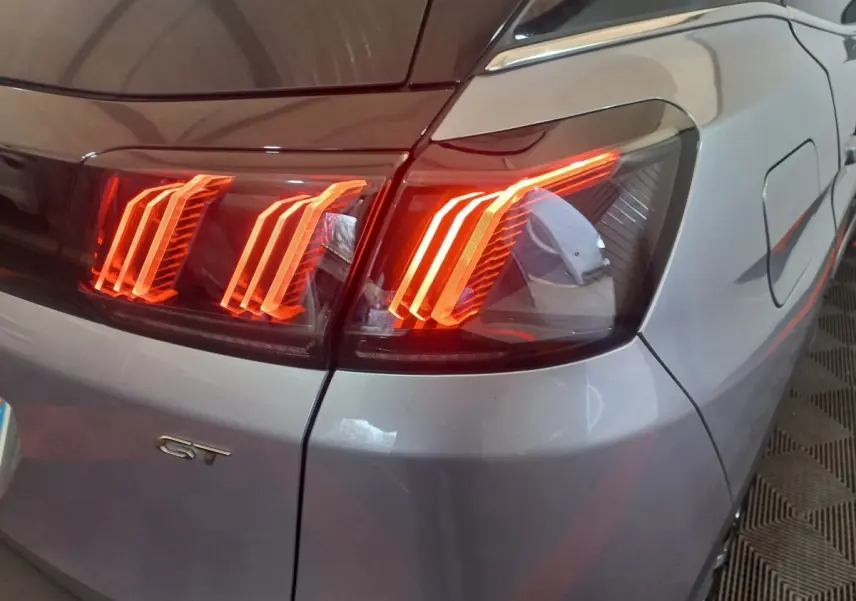 Feu arrière droit allumé d’un Peugeot 3008 GT gris clair, vue rapprochée sur la partie arrière droite.