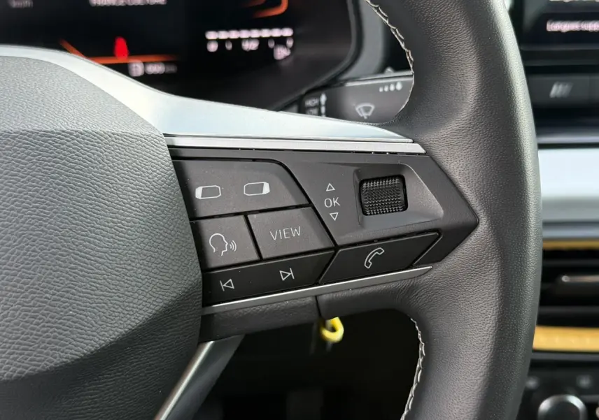 Gros plan sur les commandes multifonctions à gauche du volant du SEAT Arona TSI 115 Style 2025.