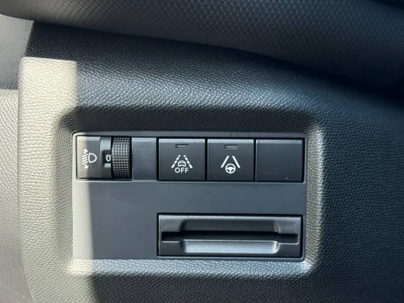 Gros plan sur les boutons de réglage d’éclairage et d’aide à la conduite du tableau de bord noir du Citroën C5 Aircross 2025.