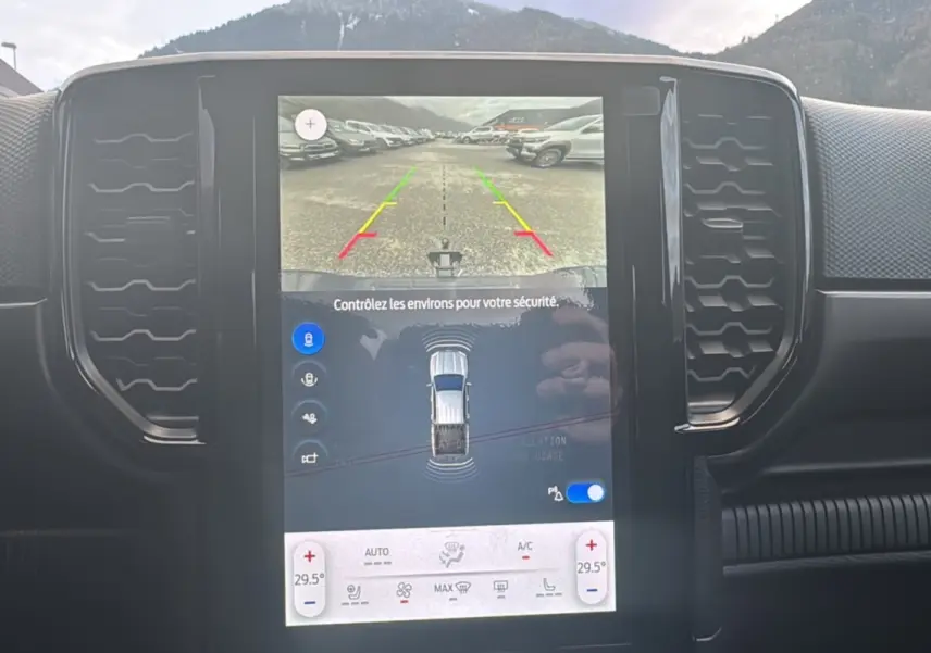 Vue rapprochée de l’écran central tactile du Ford Ranger gris Commandeur affichant la caméra de recul et les réglages climatiques.