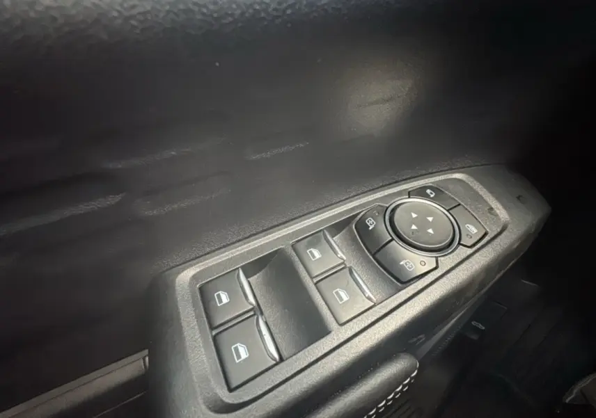 Gros plan sur les commandes des vitres électriques et rétroviseurs côté conducteur du Ford Ranger gris commandeur.