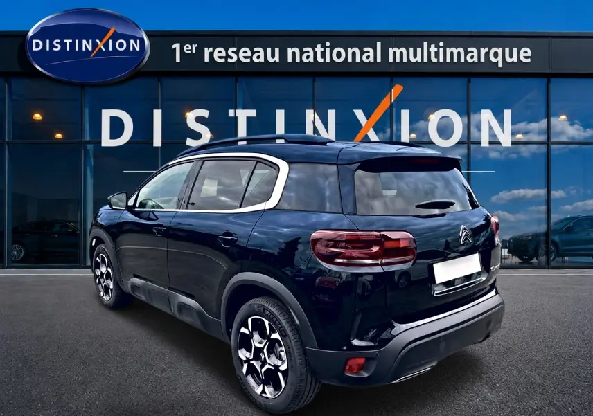 Vue 3/4 arrière droite d'un Citroën C5 Aircross noir 2025 devant une vitrine Distinxion.