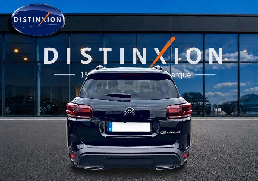 Vue arrière d'un Citroën C5 Aircross noir 2025 garé devant une vitrine avec logo Distinxion.