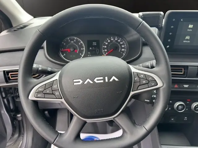Volant en similicuir de la Dacia Sandero Stepway TCE 110 gris Urban, avec commandes intégrées et tableau de bord visible.