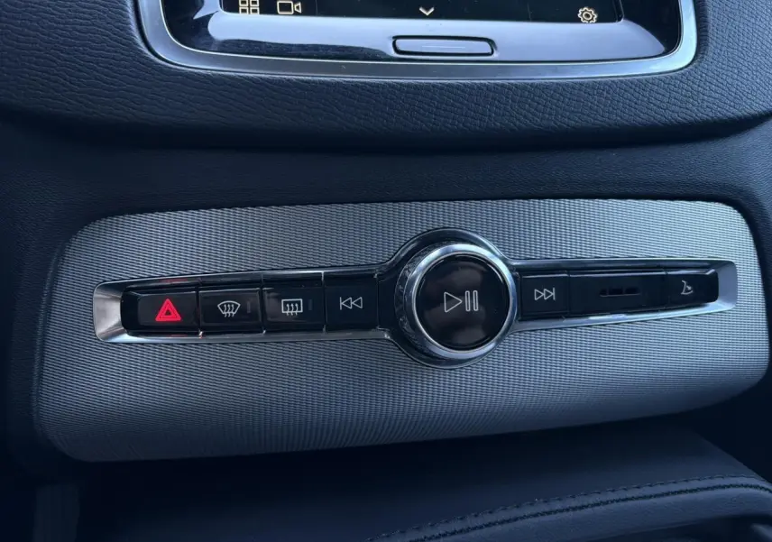Détail de la console centrale grise du Volvo XC90 2024 avec commandes multimédia et bouton de signalisation lumineux rouge.
