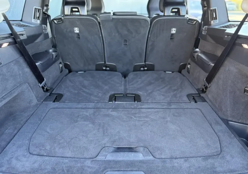 Coffre spacieux du Volvo XC90 T8 gris Platinium, sièges arrière rabattus, vue depuis l'arrière intérieur.